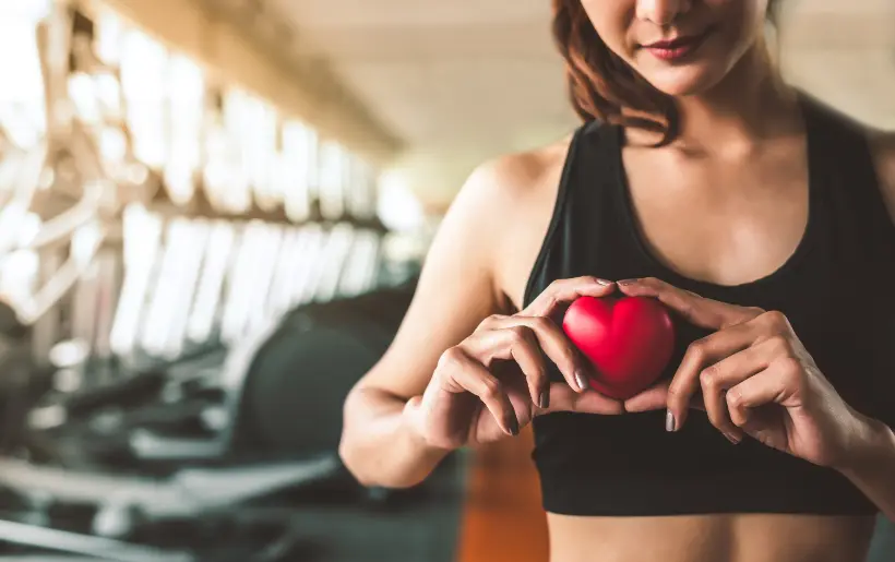 Girl holding a heart in his hand doing her workout